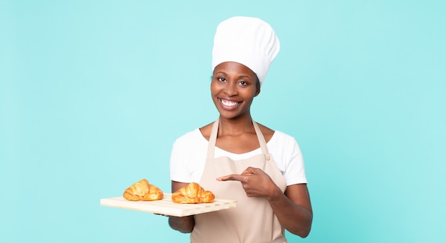 Mulher negra chef adulta segurando uma bandeja de croissants