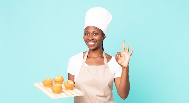 Mulher negra chef adulto afro-americano segurando uma bandeja de muffins