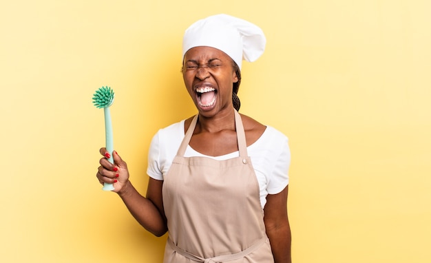 Mulher negra chef afro gritando agressivamente, parecendo muito zangada, frustrada, indignada ou irritada, gritando não. conceito de limpeza de pratos