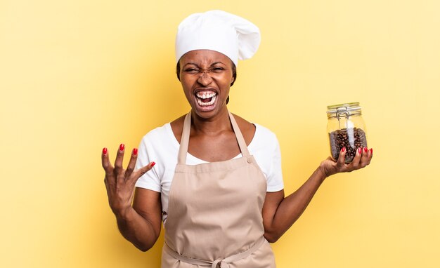 Mulher negra chef afro parecendo zangada, irritada e frustrada gritando wtf ou o que há de errado com você. conceito de grãos de café