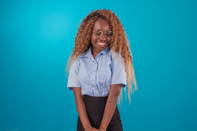 Mulher negra com cabelo encaracolado em foto de estúdio, vestindo camisa azul e saia preta e fazendo várias expressões faciais.