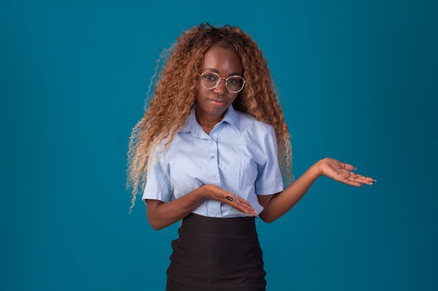 Mulher negra com cabelo encaracolado em foto de estúdio, vestindo camisa azul e saia preta e fazendo várias expressões faciais.