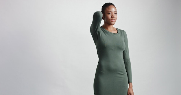Mulher negra com corte de cabelo curto no estúdio, sorrindo e vestindo um vestido.