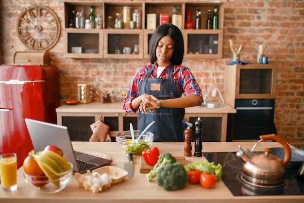 Mulher negra de avental cozinhando café da manhã saudável