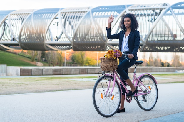 Mulher negra de negócios andando de bicicleta vintage na cidade