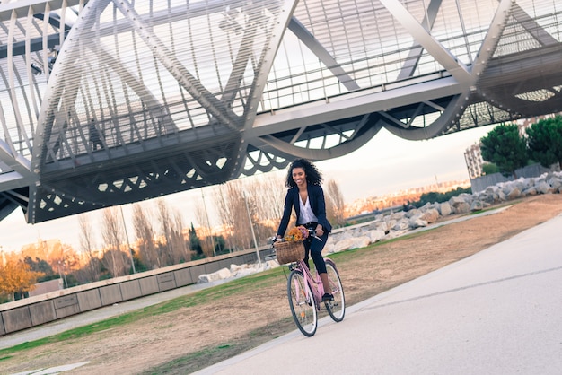 Mulher negra de negócios andando de bicicleta vintage na cidade