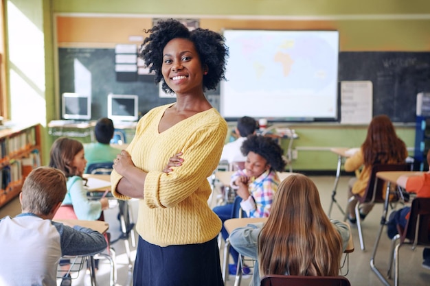 Mulher negra de retrato e professora com alunos de braços cruzados ou felicidade em uma sala de aula Educadora de rosto ou funcionária com sorriso de crianças ou educação com aprendizes de conhecimento e desenvolvimento