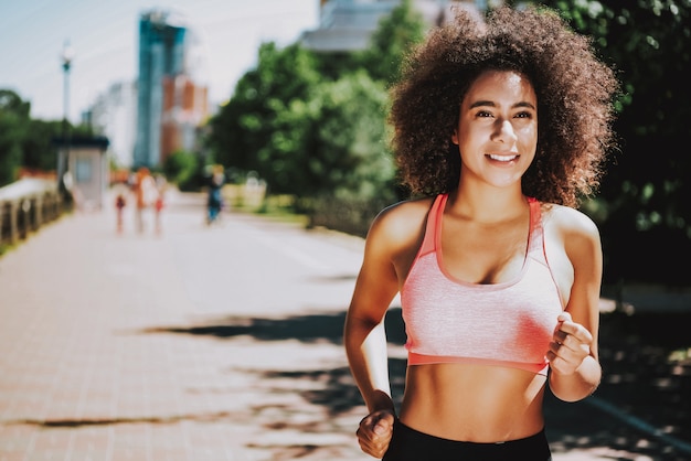 Mulher negra de sorriso no parque. Estilo de vida ativo e saudável.