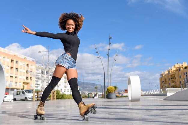 Mulher negra em patins a cavalo ao ar livre na rua urbana