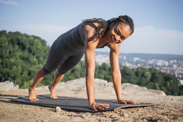 Foto mulher negra em posição de prancha no tapete de ioga