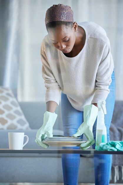 Foto mulher negra faxineira e limpeza doméstica de primavera de uma empregada profissional segurando pratos sujos empregada doméstica trabalhando e foco de uma mulher em uma sala de estar ajudando nas tarefas domésticas em uma sala