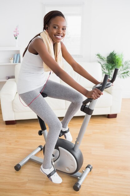 Mulher negra fazendo bicicleta de exercício com fones de ouvido