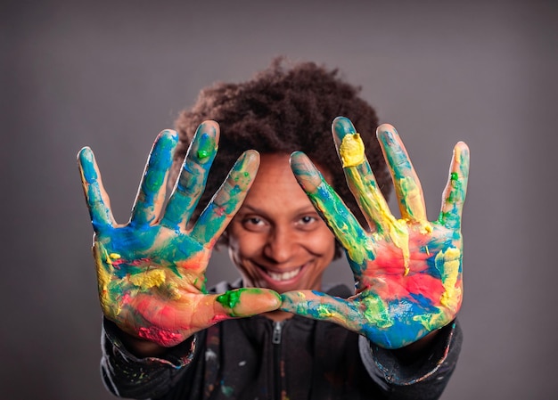 Mulher negra feliz com as mãos pintadas em um fundo cinza