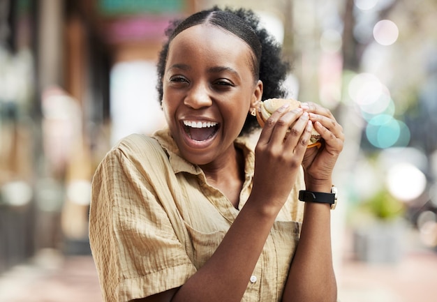 Mulher negra feliz e comendo um sanduíche de almoço ou comida no restaurante urbano da cidade ou cliente no intervalo do trabalho com felicidade Refeição de hambúrguer ou pessoa africana no brunch ou cafeteria ao ar livre