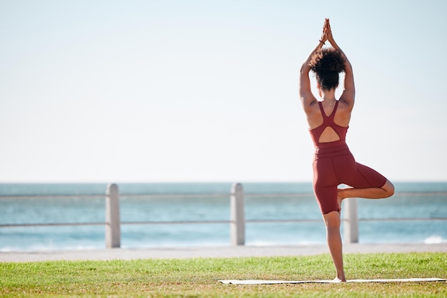 Mulher negra fitness e meditação de ioga na praia para bem-estar espiritual ou exercício na natureza Ioga feminina de pé e alongando-se no tapete em equilíbrio zen treino relaxar ou meditar na maquete