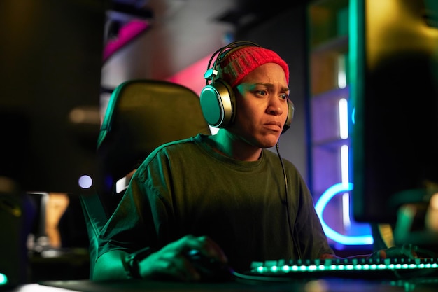 Mulher negra focada jogando videogame intenso em iluminação de néon