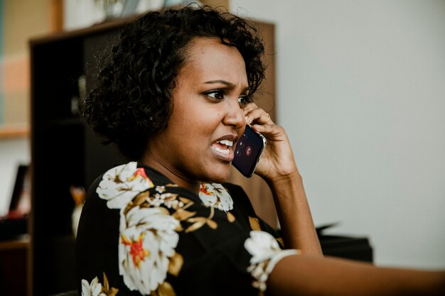 Mulher negra irritada falando ao telefone