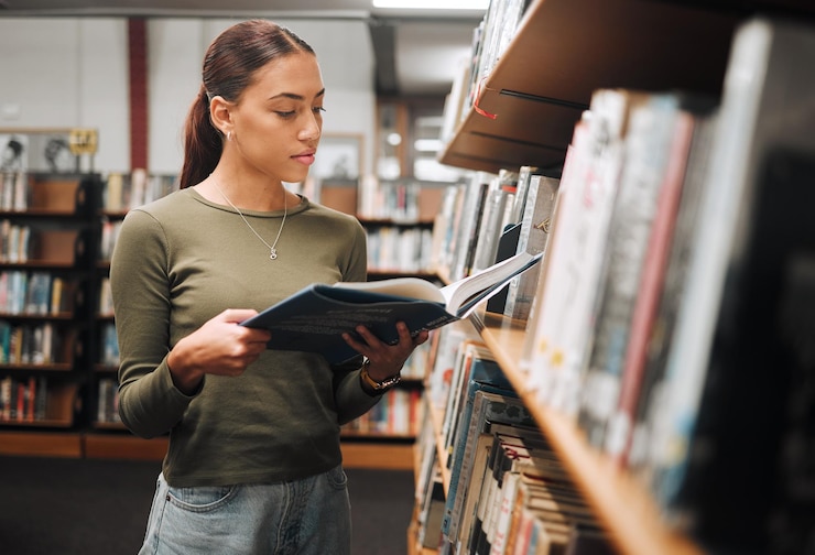 Foto mulher negra lendo livro em uma biblioteca para educação, estudando e pesquisando na universidade ou no campus da faculdade livro de foco e aluno na estante para aprendizado de idiomas ou conhecimento de filosofia