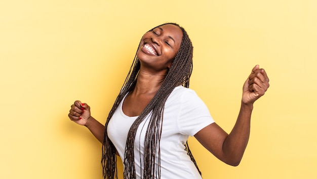 Mulher negra linda negra sorrindo, sentindo-se despreocupada, relaxada e feliz, dançando e ouvindo música, se divertindo em uma festa