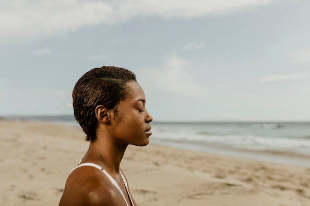 Mulher negra meditando na praia