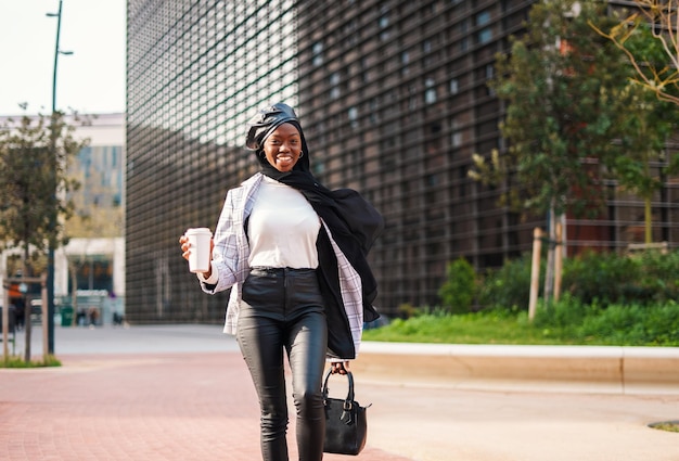 Mulher negra na moda com café para viagem correndo no trabalho