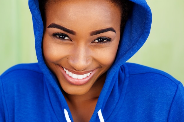 Mulher negra nova de sorriso com camisola azul