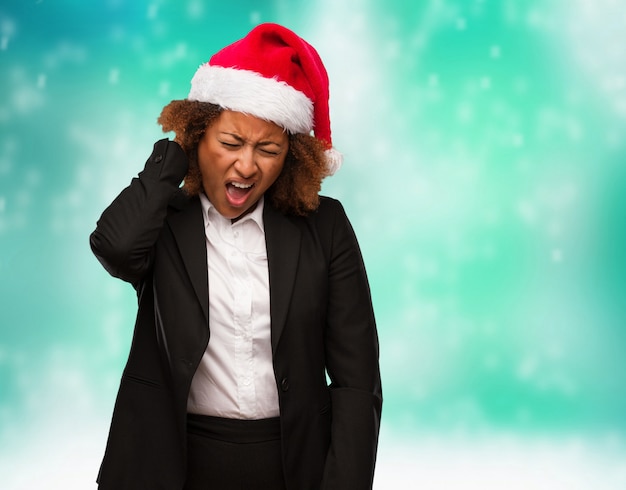 Mulher negra nova do negócio que veste um chapéu do papai noel dos chirstmas que sofre a dor de garganta