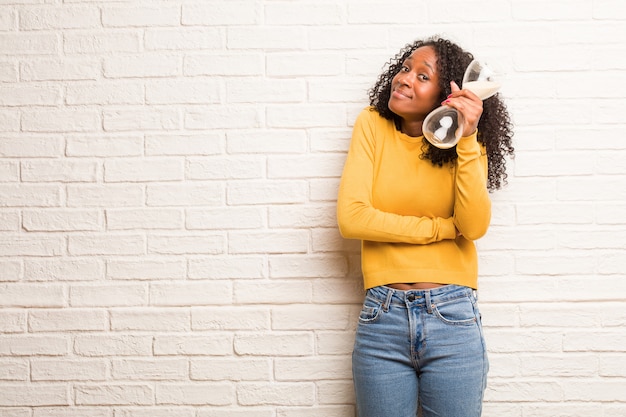 Mulher negra nova que duvida e que encolhe ombros, conceito da indecisão e insegurança, incerta sobre algo