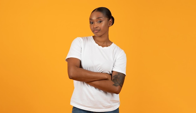 Foto mulher negra posa com os braços cruzados mostrando expressão de descontentamento estúdio