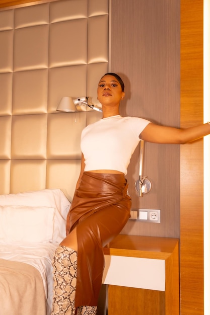 Mulher negra rica étnica no quarto de hotel ao lado do conceito de luxo de cama