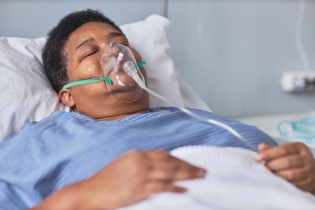 Mulher negra sênior dormindo na cama no quarto do hospital