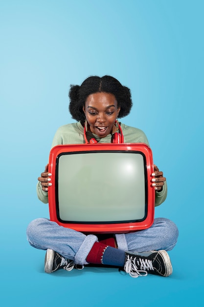 Mulher negra sentada com uma televisão retrô