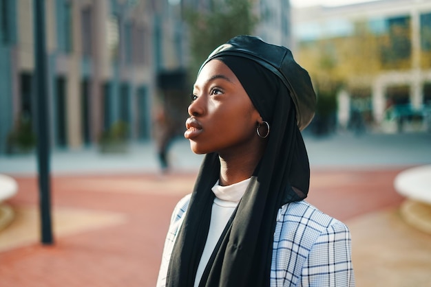 Mulher negra séria com lenço na cabeça e boina olhando atentamente para longe