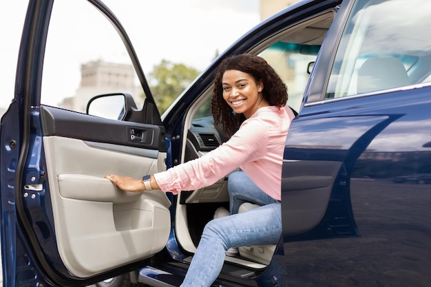 Foto mulher negra sorridente dirigindo carro novo na cidade