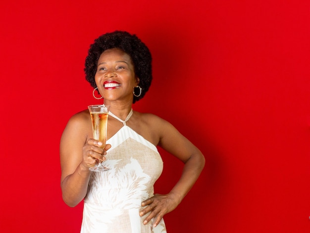 Mulher negra sorrindo e segurando uma taça com champanhe nas mãos