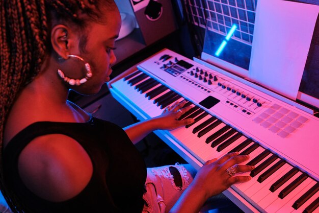 Mulher negra tocando teclado digital