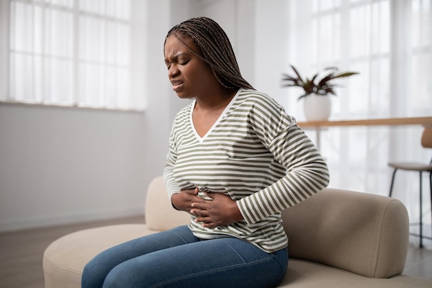 Mulher negra triste vestindo roupas casuais sofrendo de dor menstrual