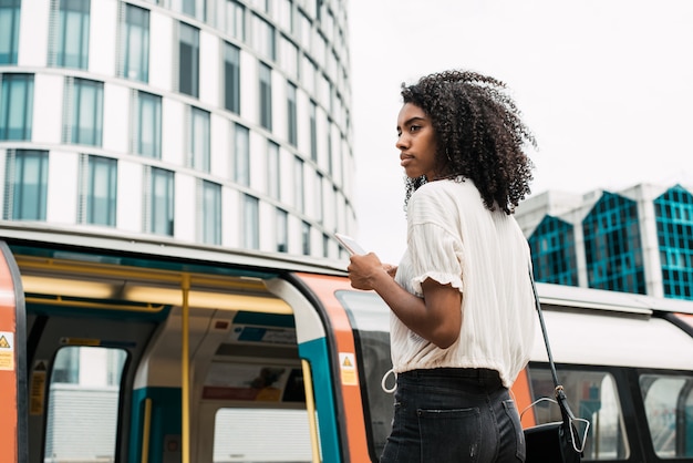 Mulher negra, usando telefone celular no metrô de londres