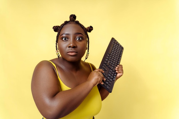 Mulher nigeriana excitada digitando olhando para monitor isolado em fundo amarelo Mulher trabalhando em computador gerente profissional