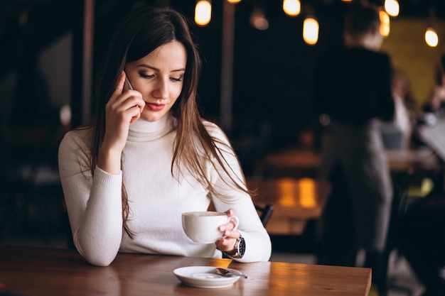 Mulher no café com telefone e café