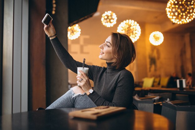 Mulher no café fazendo selfie e tomando café