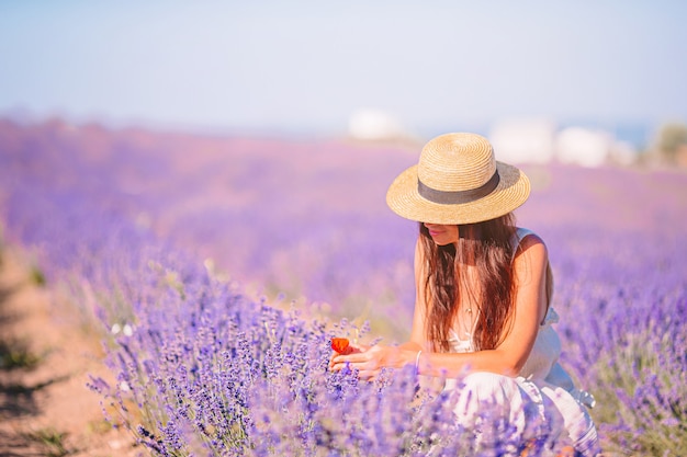 Mulher no campo de flores de lavanda ao pôr do sol em vestido e chapéu branco