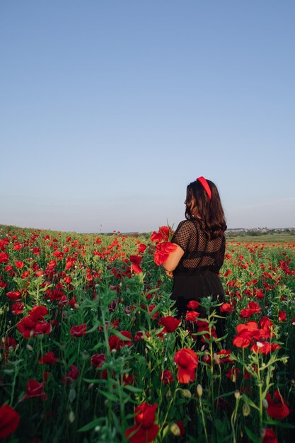 Mulher no campo de flores de papoulas no espaço de cópia do pôr do sol