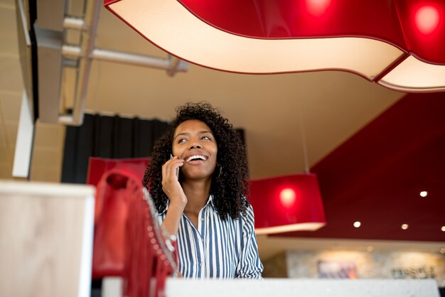 Mulher no celular, à espera de seu voo no aeroporto