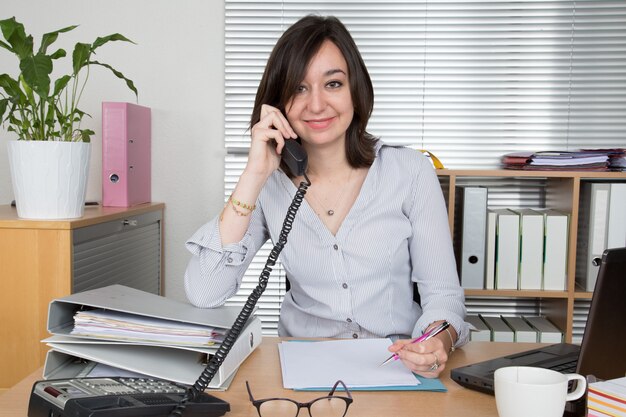 Mulher no escritório falando no celular