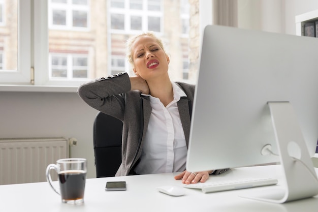 Mulher no escritório segurando o pescoço com dor