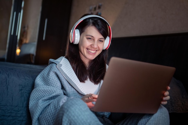Mulher no fone de ouvido trabalhando no laptop tem chamada de vídeo