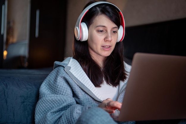 Mulher no fone de ouvido trabalhando no laptop tem trabalho remoto de videochamada em casa