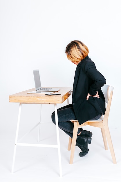 Foto mulher no local de trabalho com problemas de coluna