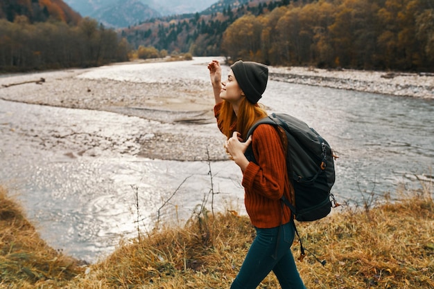 mulher no outono nas montanhas com uma mochila nos ombros viajar turismo rio foto de alta qualidade